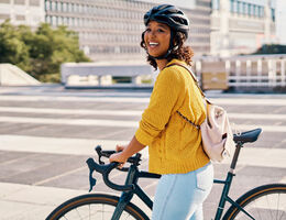 A woman pushing a bike through a parking lot.