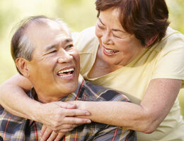 A woman hugs a man from behind.